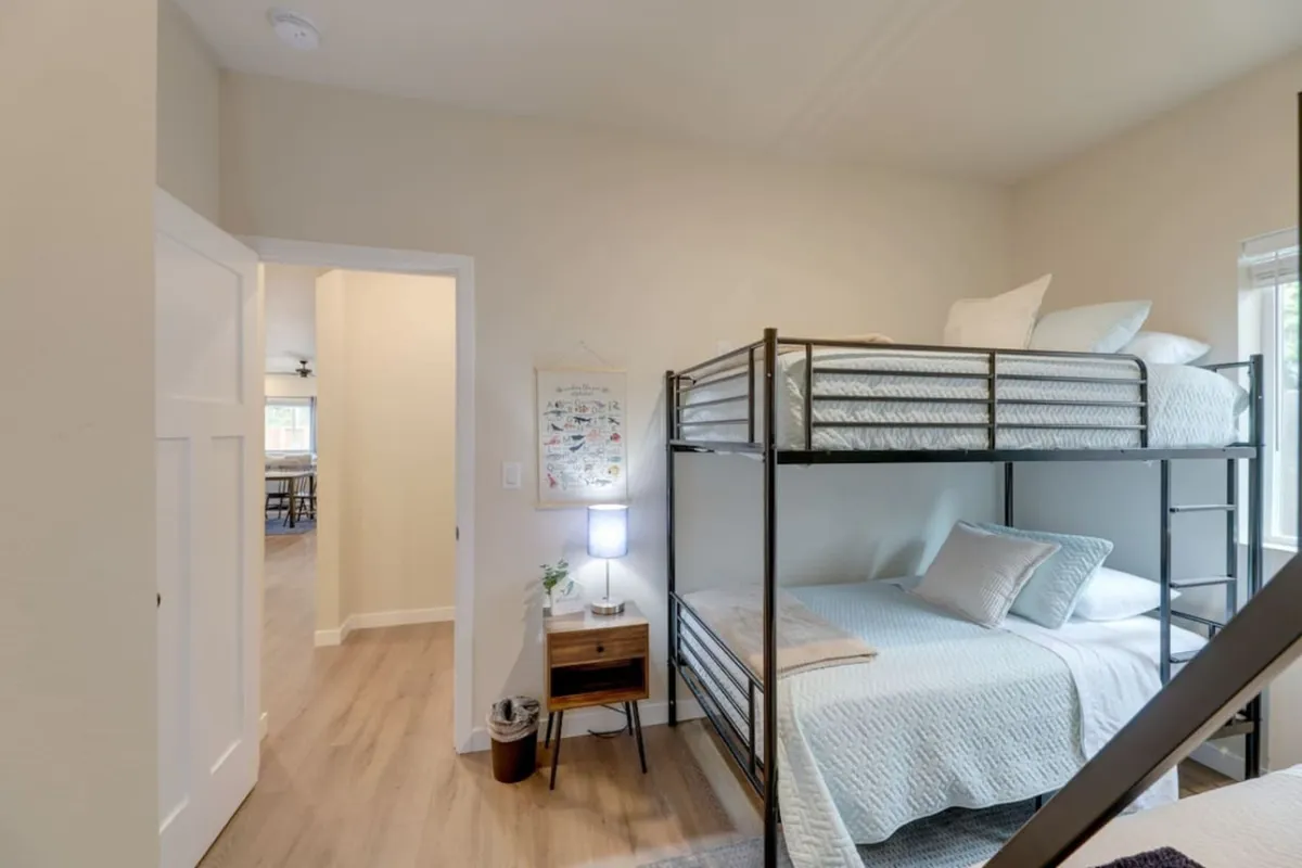A cozy bedroom with bunk beds, a nightstand, and cheerful decorative wall art, offering a comfortable space for families or kids to relax, read, and create lasting memories together.