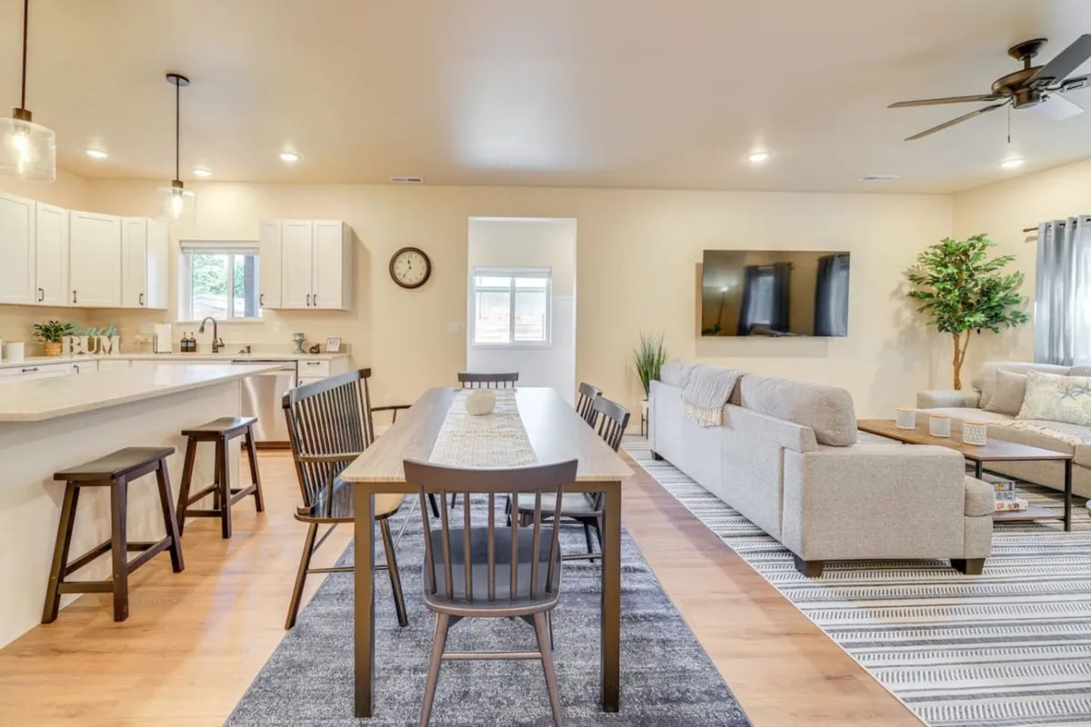 A spacious, light-filled interior connecting a dining table, sofa, TV, and kitchen counter in an open plan. The arrangement encourages conversation and activity, ideal for family meals, entertainment, or planning the next adventure together.