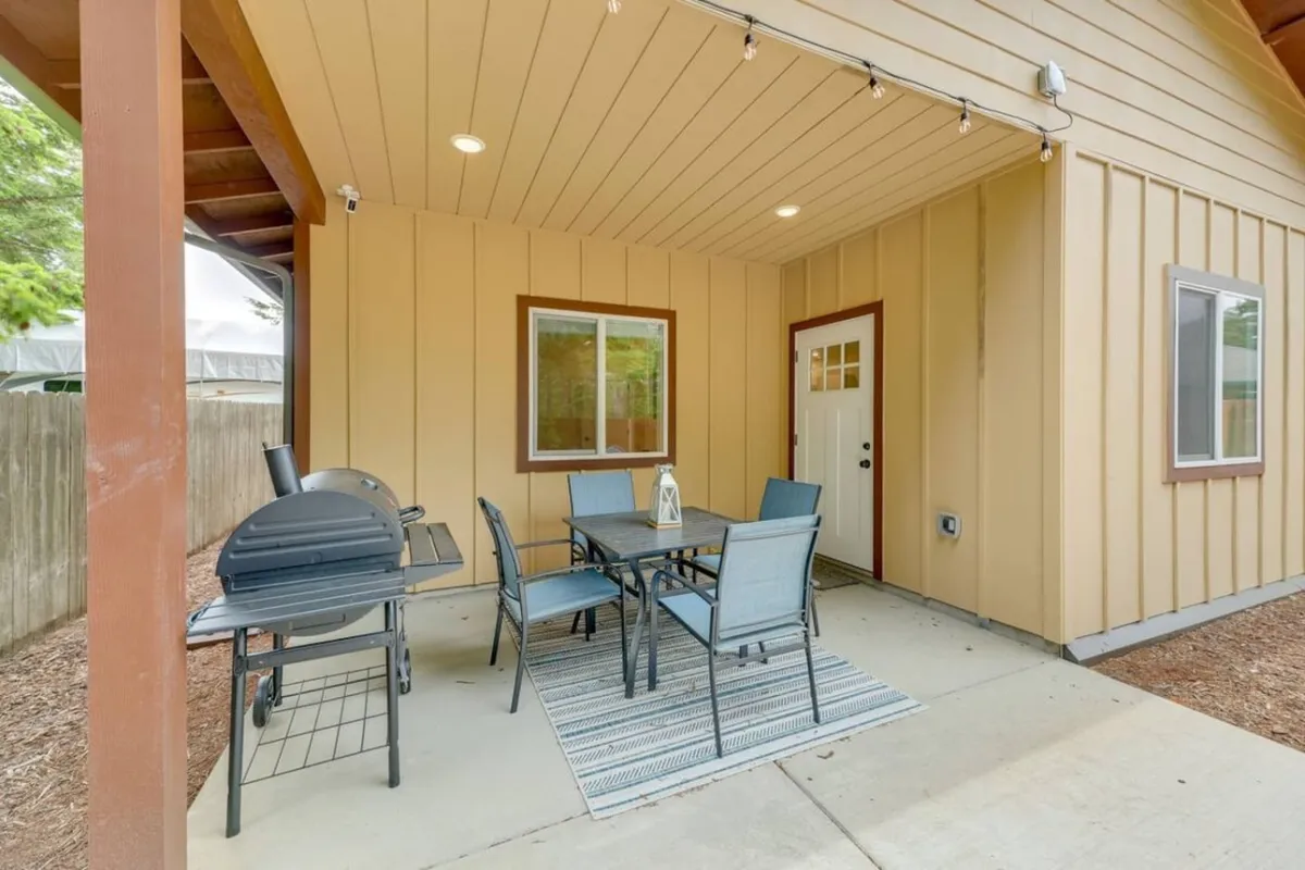 A cozy patio space furnished with outdoor seating and a grill, perfect for social gatherings or quiet mornings. The door connects directly to the home's interior, suggesting seamless movement between indoor comfort and outdoor leisure.